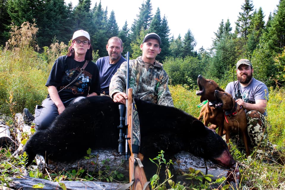 Group of People Posing with Hunted Down Black Bear