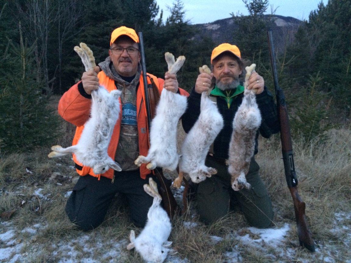 Two Men Holding Hunted Snowshoe Hare